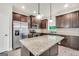 Well-lit kitchen featuring stainless steel appliances, dark wood cabinets, and a granite island at 9046 Holder Rd, Locust Grove, GA 30248