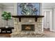 Close up of a stone fireplace with a wooden mantel and a large television above it at 120 Lapis Lake Pt, Fayetteville, GA 30215