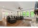 Open-concept living room with a stone fireplace, hardwood floors, and many windows overlooking the exterior at 120 Lapis Lake Pt, Fayetteville, GA 30215