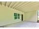 A covered patio featuring concrete flooring, exposed beams, and a window overlooking a wooded area at 120 Lapis Lake Pt, Fayetteville, GA 30215