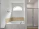 Elegant bathroom with a soaking tub, tiled surround, and a separate glass-enclosed shower at 474 Strawberry Walk, Loganville, GA 30052