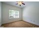 Cozy bedroom featuring plush carpet, ceiling fan, and natural light from large window at 474 Strawberry Walk, Loganville, GA 30052