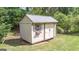 A quaint shed with a small window and decorative flower box sits on a lush green lawn at 474 Strawberry Walk, Loganville, GA 30052