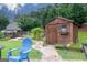 Landscaped backyard with a shed, walkway, flowering plants, and a blue patio chair in a serene setting at 2256 Long Bow Chase Nw, Kennesaw, GA 30144