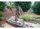 Close-up of an artful water feature with a wooden wheel, stones, and foliage creating a tranquil garden accent at 2256 Long Bow Chase Nw, Kennesaw, GA 30144