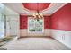 Elegant dining room featuring chandelier, wainscoting and red accent wall, open to kitchen at 1210 Magnolia Park Cir, Cumming, GA 30040