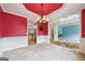 Elegant dining room featuring chandelier, wainscoting and red accent wall, open to living room at 1210 Magnolia Park Cir, Cumming, GA 30040