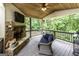 Inviting covered patio with stone fireplace, cozy furniture, and serene views of the natural surroundings at 101 High Bluff Trl, Carrollton, GA 30116
