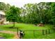 Expansive backyard featuring a large lawn with playset, swing, mature trees, and lush landscaping at 150 Sandy Ridge Trl, Fayetteville, GA 30214