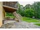 Covered patio with stone flooring, stairs leading to the upper screened porch, and a view of the lush backyard at 150 Sandy Ridge Trl, Fayetteville, GA 30214