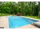 Backyard pool with a diving board, surrounded by mature trees and green grass, perfect for summer relaxation at 150 Sandy Ridge Trl, Fayetteville, GA 30214