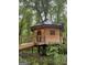 Whimsical treehouse with wooden siding, metal roof, and a ramp leading to the entrance nestled in trees at 6290 Cascade Palmetto Hwy, Fairburn, GA 30213