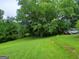Large grassy backyard surrounded by mature trees, and a car parked on the side of the house at 920 Courthouse Rd, Temple, GA 30179