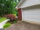 Attached garage with white door and brick side, surrounded by lush landscaping at 920 Courthouse Rd, Temple, GA 30179