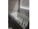 Bright bathroom featuring a soaking tub with chrome fixtures and sunlight streaming through the window blinds at 1049 Homer Ln, Stockbridge, GA 30281
