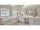 Bright bathroom featuring a soaking tub, double vanity with white cabinets, and a large mirror at 165 Hidden Lake Dr, Fayetteville, GA 30215