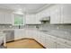 White kitchen features custom cabinets, stainless appliances, granite countertops, and a window view at 165 Hidden Lake Dr, Fayetteville, GA 30215