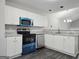 Bright kitchen featuring white cabinets, granite countertops, modern blue appliances, and dark wood flooring at 3075 Lakeside Cir, Covington, GA 30016