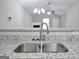 Close-up of granite countertops, stainless steel sink, modern faucet and breakfast bar overlooking the living area at 3075 Lakeside Cir, Covington, GA 30016