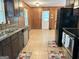Well-lit kitchen with tile floor, wood paneling, black appliances, and stainless steel sink at 503 Roy Huie Rd, Riverdale, GA 30274