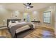 Virtually staged main bedroom with wood floors, large windows, a ceiling fan, and modern decor at 2436 Green Hollow Ct, Conyers, GA 30012