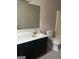 Bathroom with a black vanity, light countertop, a large mirror, and a shower-tub combination at 1321 Lakeview Nw Dr, Conyers, GA 30012