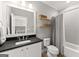 Bathroom with a black countertop, modern sink, and tiled bath, complemented by wooden shelves for storage at 1104 Victoria Ne St, Atlanta, GA 30319