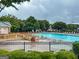 A community pool with ample seating, surrounded by lush greenery and mature trees on a cloudy day at 1765 Neighborhood Walk, Mcdonough, GA 30252