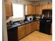 Kitchen with wood cabinets, dark countertops, black appliances, and wood floors at 5658 Wind Gate Ln, Lithonia, GA 30058