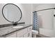 Bathroom featuring a vanity with granite countertop, round mirror, toilet, and shower-tub combination at 5745 Westwood Dr, Cumming, GA 30040