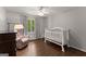 Bedroom with hardwood floors, a white crib, and a patterned chair at 4680 Brighton Lake Dr, Cumming, GA 30040