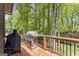 Back deck with grilling area and natural views surrounded by lush trees and a wood railing at 4680 Brighton Lake Dr, Cumming, GA 30040