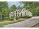 Elegant home featuring lush landscaping, a winding driveway, and an attached garage at 5940 Plantation Dr, Roswell, GA 30075