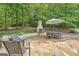 Stone patio with outdoor seating and fireplace nestled in a serene backyard setting at 5940 Plantation Dr, Roswell, GA 30075
