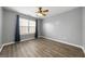 A well-lit bedroom featuring neutral walls, a ceiling fan, a large window, and wood-look laminate flooring at 1535 Fenmore St, Lithia Springs, GA 30122