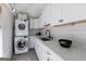 Bright laundry room featuring a stacked washer and dryer and white cabinetry with a sink at 381 Cherokee Se Ave, Atlanta, GA 30312