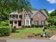 Stately brick home with a covered porch and manicured front lawn and established shrubs at 151 Overhill Point, Alpharetta, GA 30005