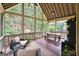 Relaxing screened porch with comfortable seating, wooden flooring, and views of the wooded area at 151 Overhill Point, Alpharetta, GA 30005