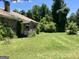 Side exterior view of an abandoned property with a stone facade and overgrown lawn at 72 N Pomona N Rd, Hampton, GA 30228
