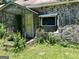 Close-up of the exterior showing a stone facade, porch, door and broken window at 72 N Pomona N Rd, Hampton, GA 30228
