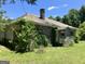Exterior view of a stone-clad home with an overgrown yard needing landscaping and repair at 72 N Pomona N Rd, Hampton, GA 30228