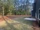 View of a spacious backyard with a mix of grass and pine straw and newly built dark home exterior at 142 Tye St, Stockbridge, GA 30281
