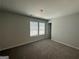 Bright bedroom with neutral walls and carpet, featuring a window with blinds and a door at 142 Tye St, Stockbridge, GA 30281
