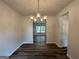 Well-lit dining room features hardwood floors, neutral walls, and a modern chandelier; a window and doorway add dimension at 142 Tye St, Stockbridge, GA 30281