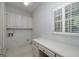 Functional laundry room with overhead cabinets, a desk, and a window at 170 Glen Eagle Way, Mcdonough, GA 30253