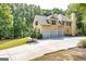 Spacious home showcasing a three-car garage, a paved driveway, and lush landscaping at 235 Ashley Forest Dr, Fayetteville, GA 30214