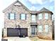 Two-story brick home with a basketball hoop, attached garage, and a welcoming blue front door at 413 Atlas Ct, Locust Grove, GA 30248