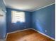 Blue bedroom with hardwood floors, a window, and minimalist decor, bathed in natural light at 6214 Crestview Se Dr, Covington, GA 30014