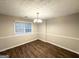 Formal dining room featuring a chandelier, wainscoting, a large window, and wood-look vinyl flooring at 9124 Comstock Ct, Covington, GA 30014