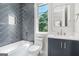 Stylish bathroom featuring a tub, shower, and sleek blue vanity with a view from the window at 115 Thome, Alpharetta, GA 30022